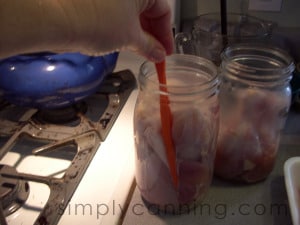 Removing air bubbles from a jar of raw chicken.