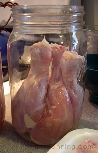 Raw chicken drumsticks packed into clean canning jar.