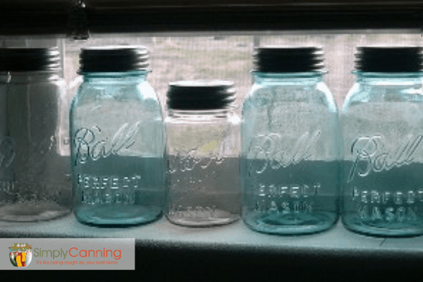 Blue and clear glass canning jars sitting in a windowsill.