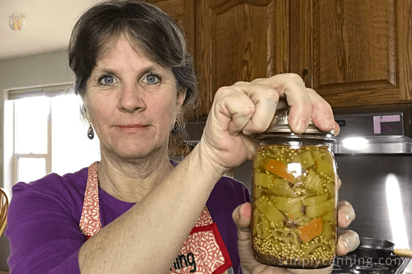 Sharon tightening the ring on a jar filled with peppers.