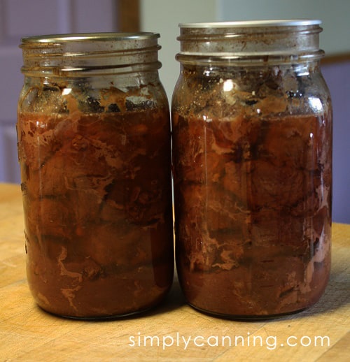 Meat canned in quart jars that are sitting on the countertop.