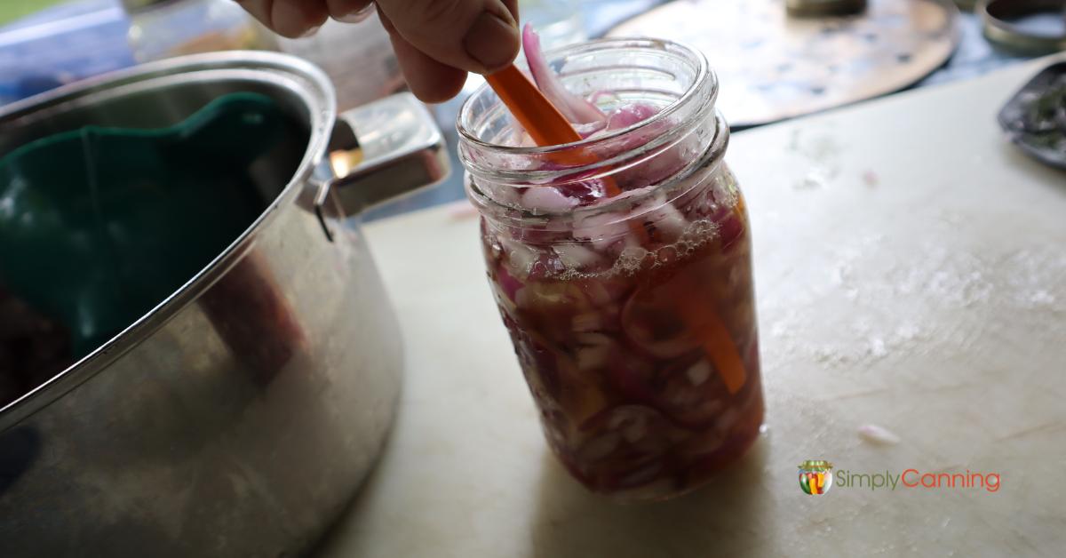 Jar of onions and honey sauce, demonstrating how to debubble with an orange peeler.