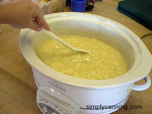 Stirring pale pear puree that is cooking down in the CrockPot.