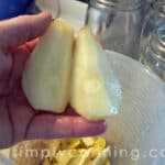 Holding juicy peeled pear quarters over a bowl of scraps.
