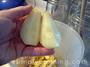 Holding juicy peeled pear quarters over a bowl of scraps.