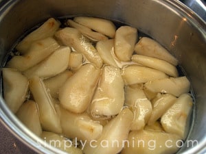 Pear slices floating in syrup to keep them from turning brown.