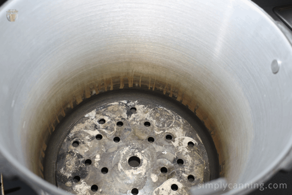 A canning rack sitting on the bottom of a pressure canner.