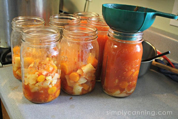 Various canning jars filled half of the way with solid ingredients and one jar filled with solid and liquid ingredients.