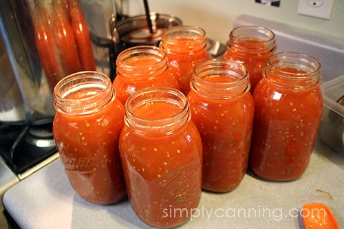 Seven open quart canning jars filled with the stewed tomatoes mixture.