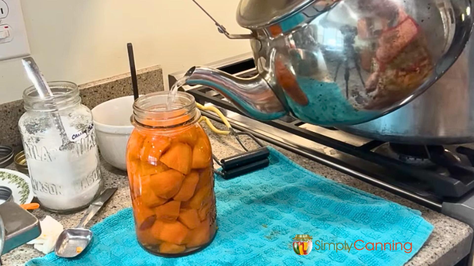 Using a teapot for the hot water filling a jar of sweet potatoes to go in the canner. 