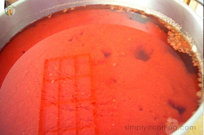 A clear layer of tomato liquid floating on top of the solid layer of tomatoes.