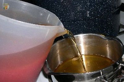 Tomato whey or broth being poured from the plastic pitcher into another pot.