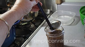 Placing a flat lid on a jar of ground venison using the magnetic lid lifter tool.