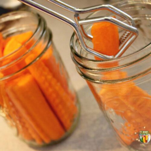 Using tongs to put carrot sticks into clean canning jars.
