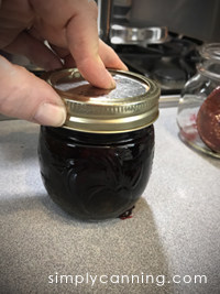 Tightening the screw band of a jar of cherry jam.