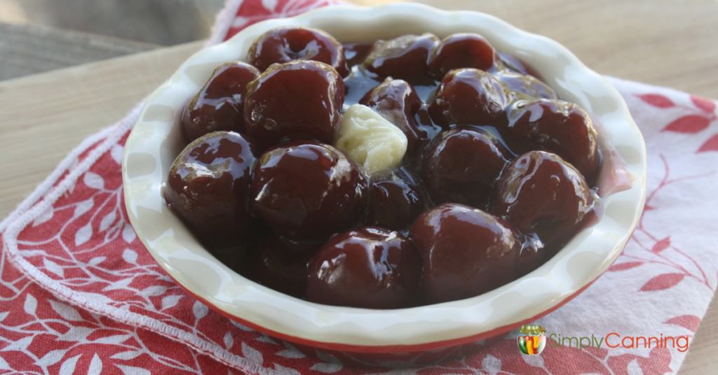 A pie plate filled with cherry pie filling and dotted with butter.