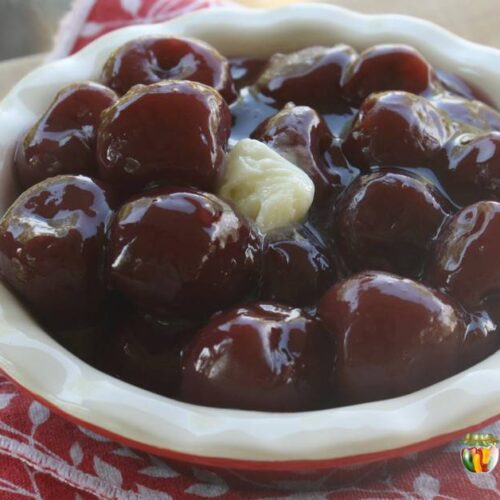 A pie plate filled with cherry pie filling and dotted with butter.