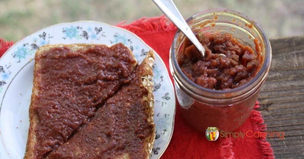 Chokecherry jelly spread on toast with an open jar of jelly to its side.