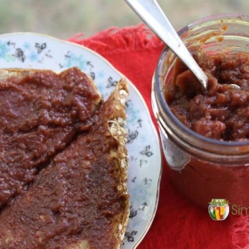 Chokecherry jelly spread on toast with an open jar of jelly to its side.