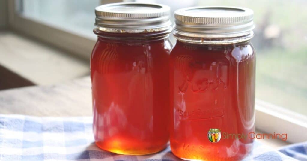 Two jars of clear, bright red crabapple jelly.