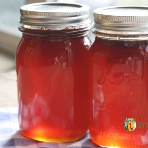 Two jars of clear, bright red crabapple jelly.