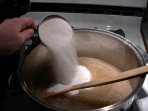 Pouring sugar into the dandelion tea to make jelly.