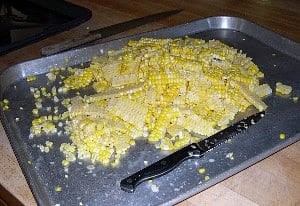 A cookie sheet filled with corn kernels cut directly off the cobs.