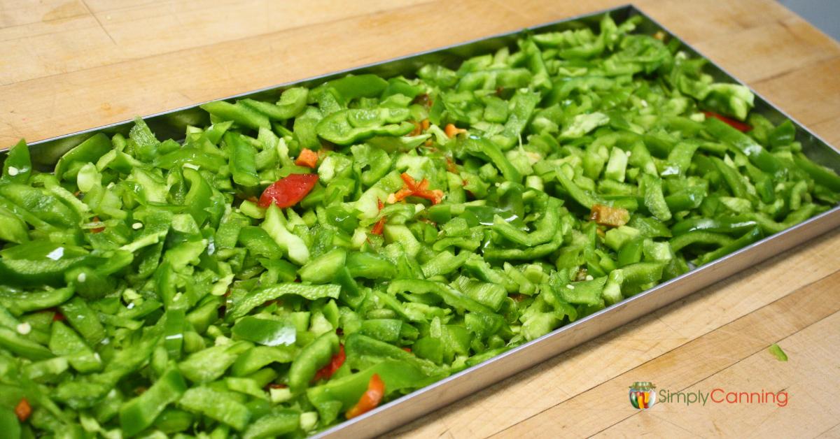 Freeze dryer tray filled with fresh green peppers and a few red peppers mixed in, ready to be freeze dried.
