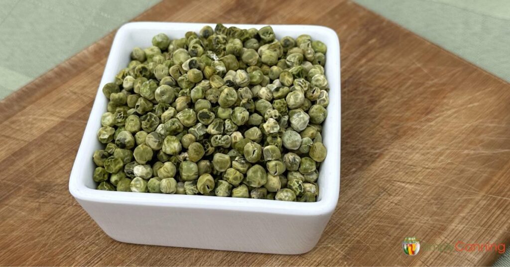 A square bowl filled with dark green dehydrated peas.
