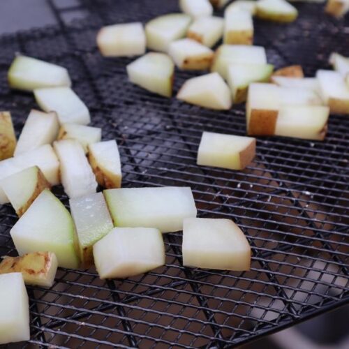 Spreading small pieces of raw potatoes over dehydrator trays.