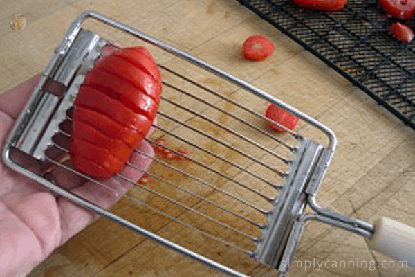 Slicing a long tomato using the vintage tomato slicing tool.