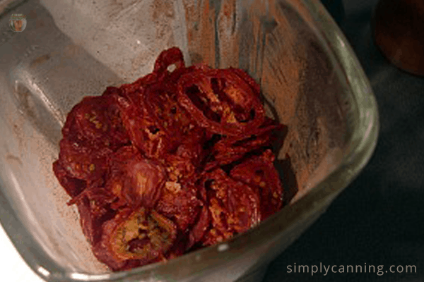 A blender filled with partially pulverized dried tomato slices.