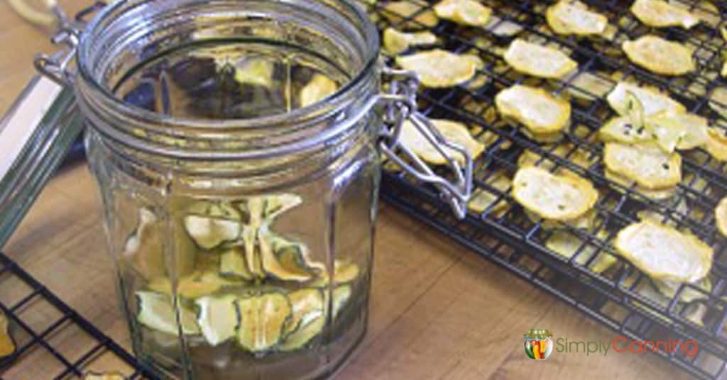 Putting dehydrated zucchini into a snap close jar.