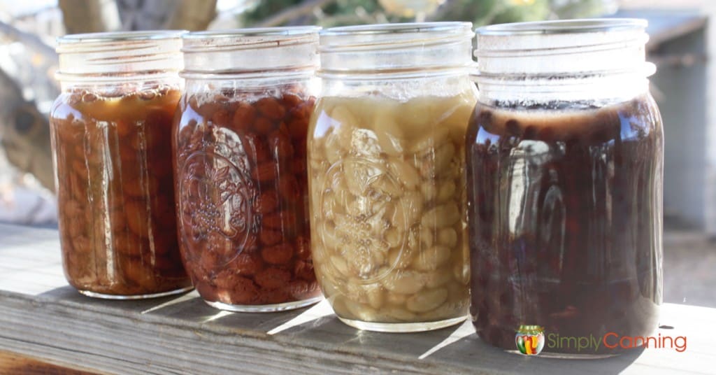 Jars filled with various colors of cooked dry beans.