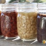 Jars filled with various colors of cooked dry beans.