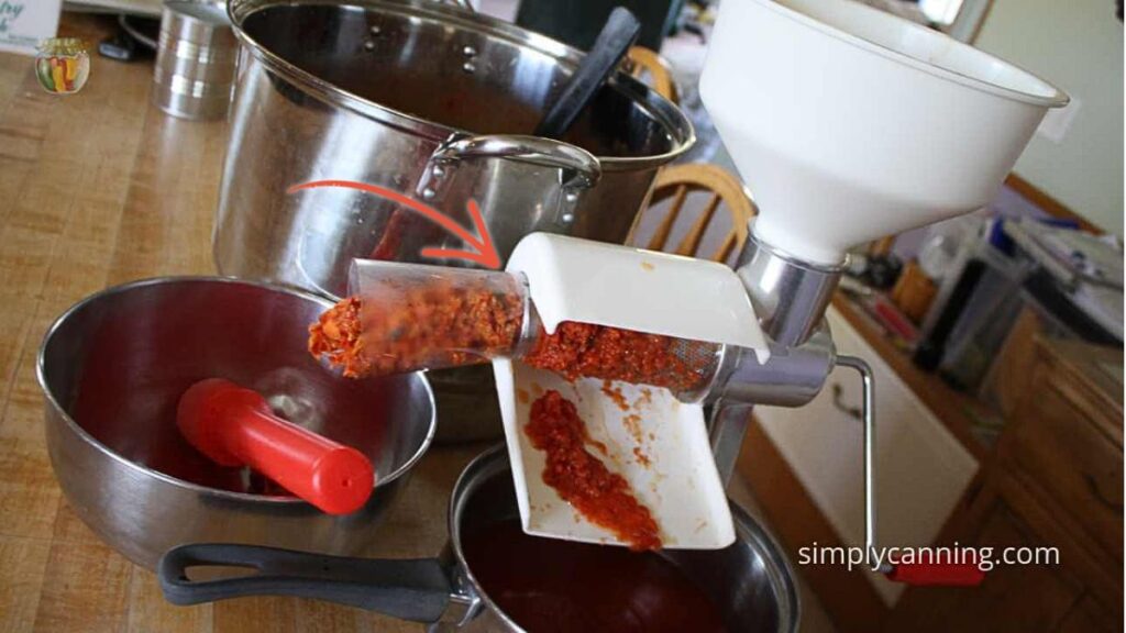 Food strainer attached to the counter with tomatoes being milled.