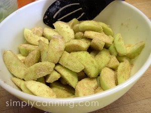 Stirring to coat prepared apple slices with the sugar mixture.