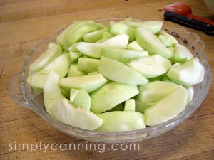 A pie plate filled with peeled and sliced apples.