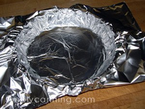 Lining a pie plate with aluminum foil.