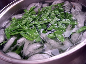 Blanched peas floating in icewater.