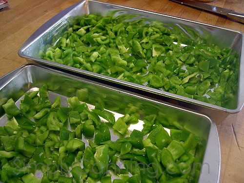 Chopped green peppers spread evenly over cookie sheets or trays for freezing.