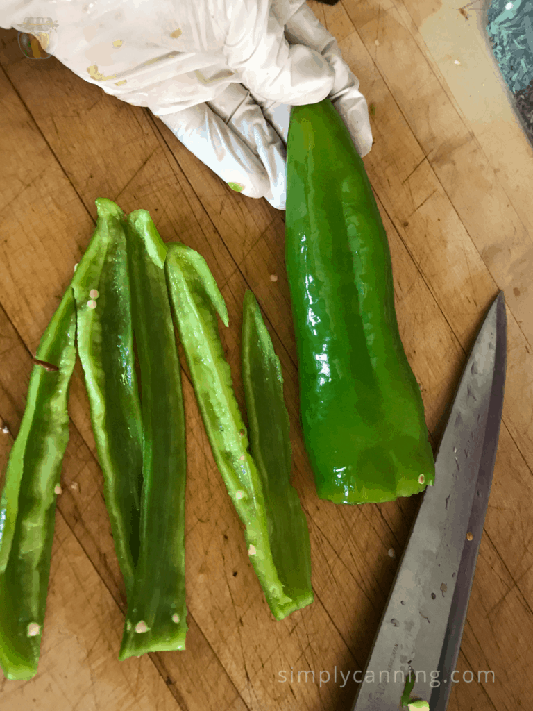 Slicing long green peppers into pieces using a sharp knife.