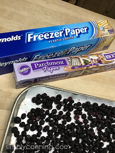 Boxes of freezer and parchment paper sitting next to a tray of raspberries.