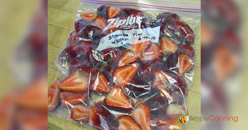 A freezer bag packed tightly with sliced strawberries and labeled with the date.