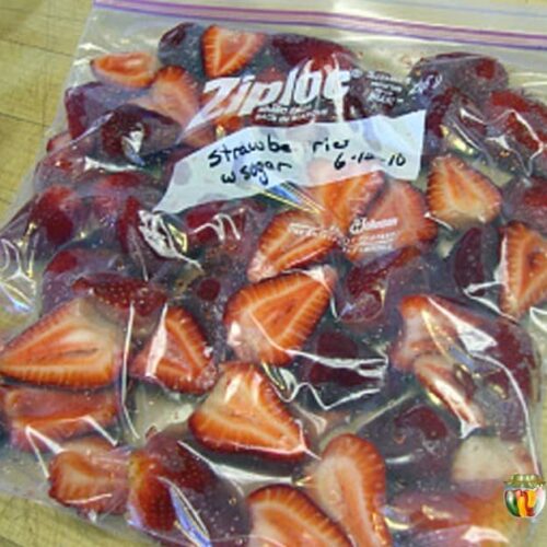 A freezer bag packed tightly with sliced strawberries and labeled with the date.
