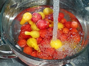 Running water over a bowl of frozen cherry and pear tomatoes.