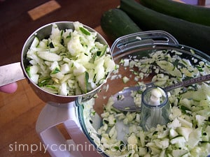 Measuring out grated zucchini from the food processor bowl.