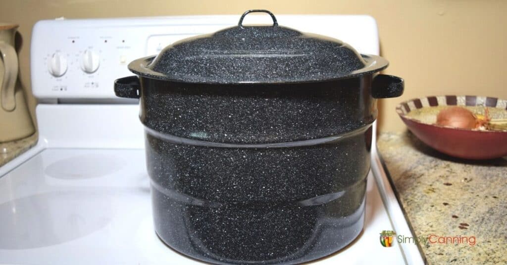 A graniteware canner sitting on a white glasstop stove.