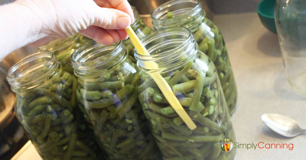 Using an orange peeler to remove bubbles from jars packed with green beans.