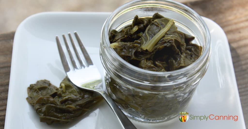 A small jar filled with cooked greens and a fork to the side.